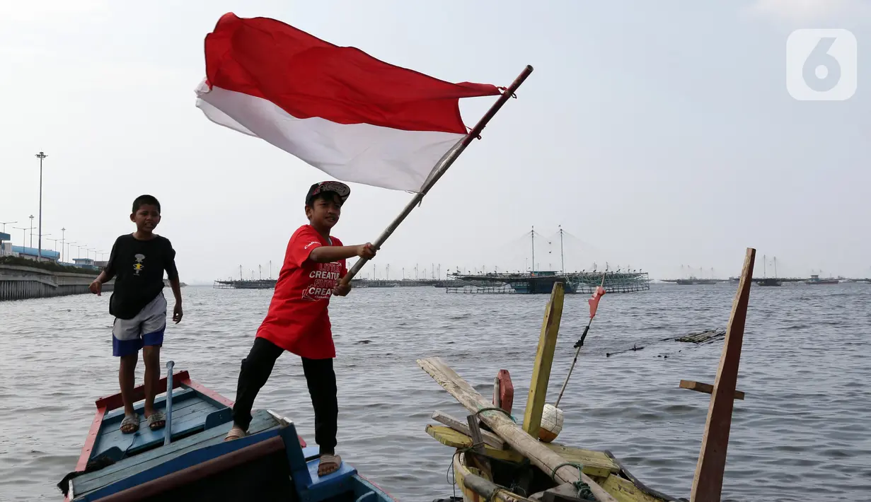 Seorang anak mengibar-ngibarkan bendera Merah Putih usai pelaksanaan Upacara Peringatan HUT RI ke-77 di Kawasan Kalibaru Barat, Cilincing, Jakarta, Rabu (17/8/2022). Memperingati Hari Kemerdekaan Indonesia ke-77, anak-anak yang tergabung dalam Kelas Jurnalis Cilik bersama para relawan melaksanakan upacara bendera dan beragam lomba. (Liputan6.com/Helmi Fithriansyah)