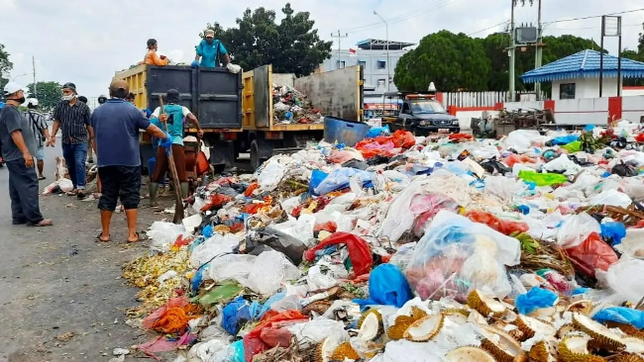 Petugas kebersihan mengangkut tumpukan sampah di Pekanbaru dengan fasilitas operasional terbatas.