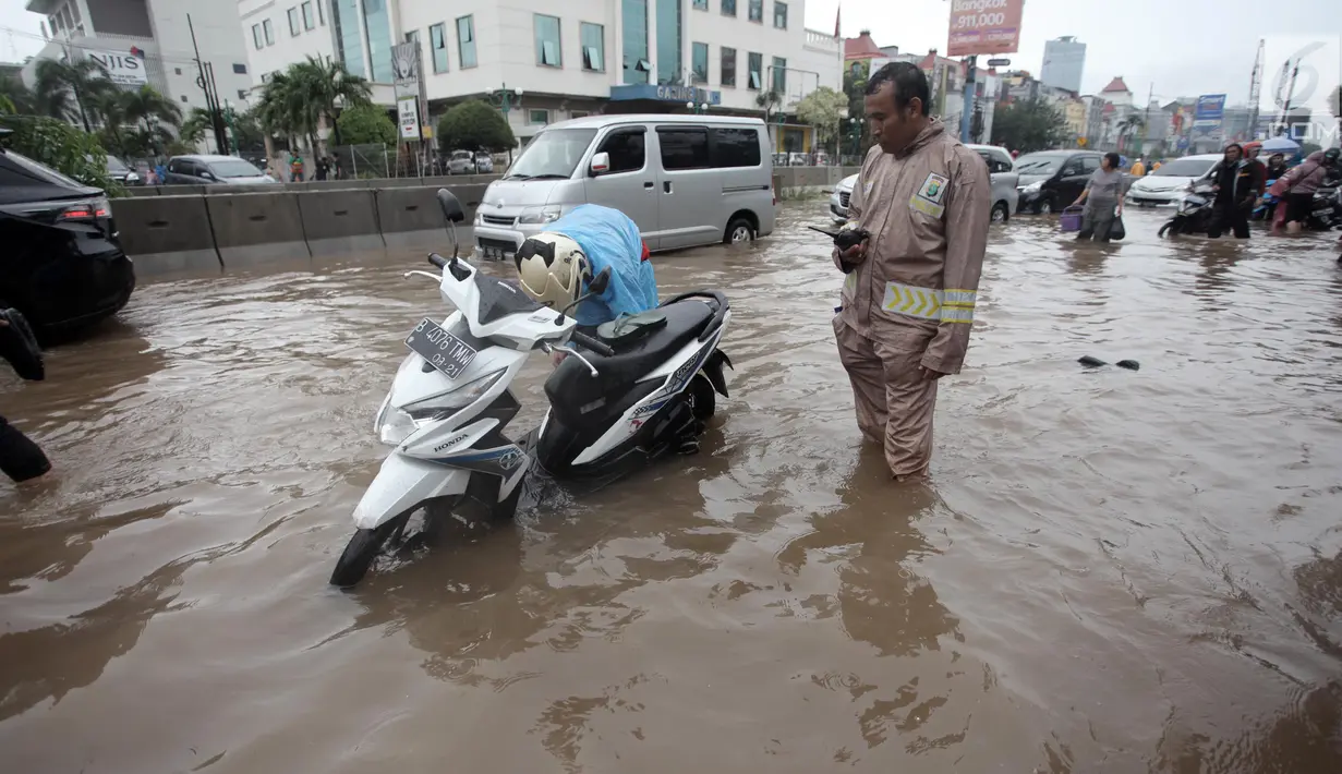 Seorang pengendara memperbaiki motornya yang mogok saat melintasi banjir di Jalan Boulevard Barat Raya, Kelapa Gading, Jakarta, Kamis (15/2). Hujan lebat yang mengguyur Jakarta mengakibatkan sejumlah wilayah terendam banjir. (Liputan6.com/Arya Manggala)