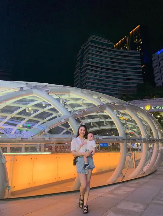 Sambil momong buah hati, Marcella terlihat tetap kece dengan white shirt dan asymmetric skirt.