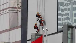 Pekerja membersihkan salah satu gedung bertingkat di Bundaran Hotel Indonesia, Jakarta, Rabu (14/3). BPJS Ketenagakerjaan mengeluarkan nilai klaim Rp 971 miliar sepanjang 2017. (Liputan6.com/Angga Yuniar)
