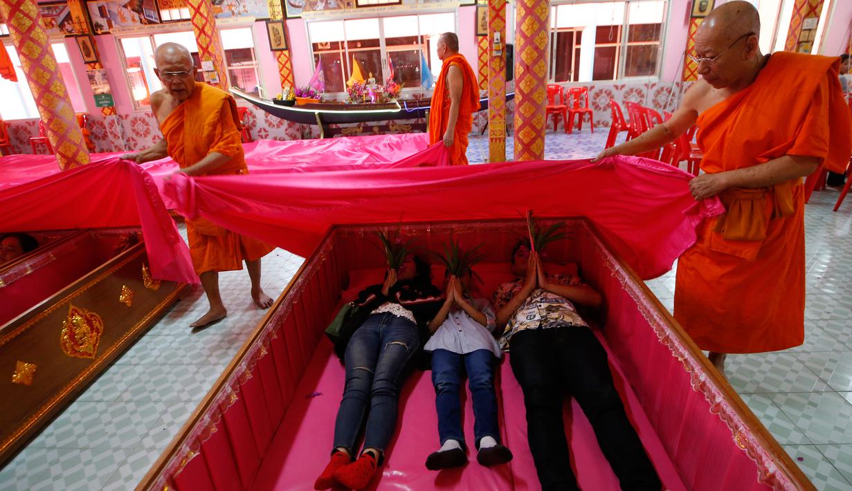 Sejumlah biksu menutup para pemuja dengan kain berwarna merah muda ketika mereka secara bergiliran berbaring dalam peti mati selama mengikuti ritual keagamaan di kuil Takien, pinggiran kota Bangkok, Thailand, Senin (31/12). (AP/Sakchai lalit)