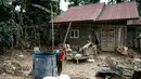 Lumpur sisa banjir, debu, serta kualitas udara yang menurun menjadi faktor utama yang dapat memperburuk kesehatan anak-anak, terutama saluran pernapasan. Tampak dalam foto, seorang anak perempuan mengambil air dari tangki penyimpanan di Babo, Aceh Tamiang, pada Senin 15 Desember 2025. (Yasuyoshi CHIBA/AFP)