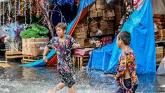 Anak-anak bermain di tengah banjir usai hujan deras yang tiba-tiba mengguyur di sebuah pasar dekorasi Natal di Manila, Filipina (9/12/2020). (Xinhua/Rouelle Umali)