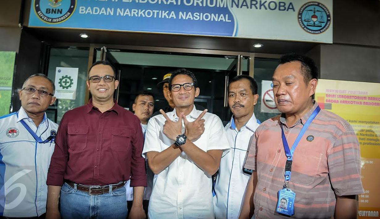 Pasangan Anies Baswedan dan Sandiaga Uno mengenalkan salam jari saat menyapa wartawan di BNN, Jakarta, Minggu (25/9). Anies-Sandiaga akan menjalani tes bebas narkoba dengan mengikuti serangkaian tes meliputi urine dan rambut. (Liputan6.com/Faizal Fanani)
