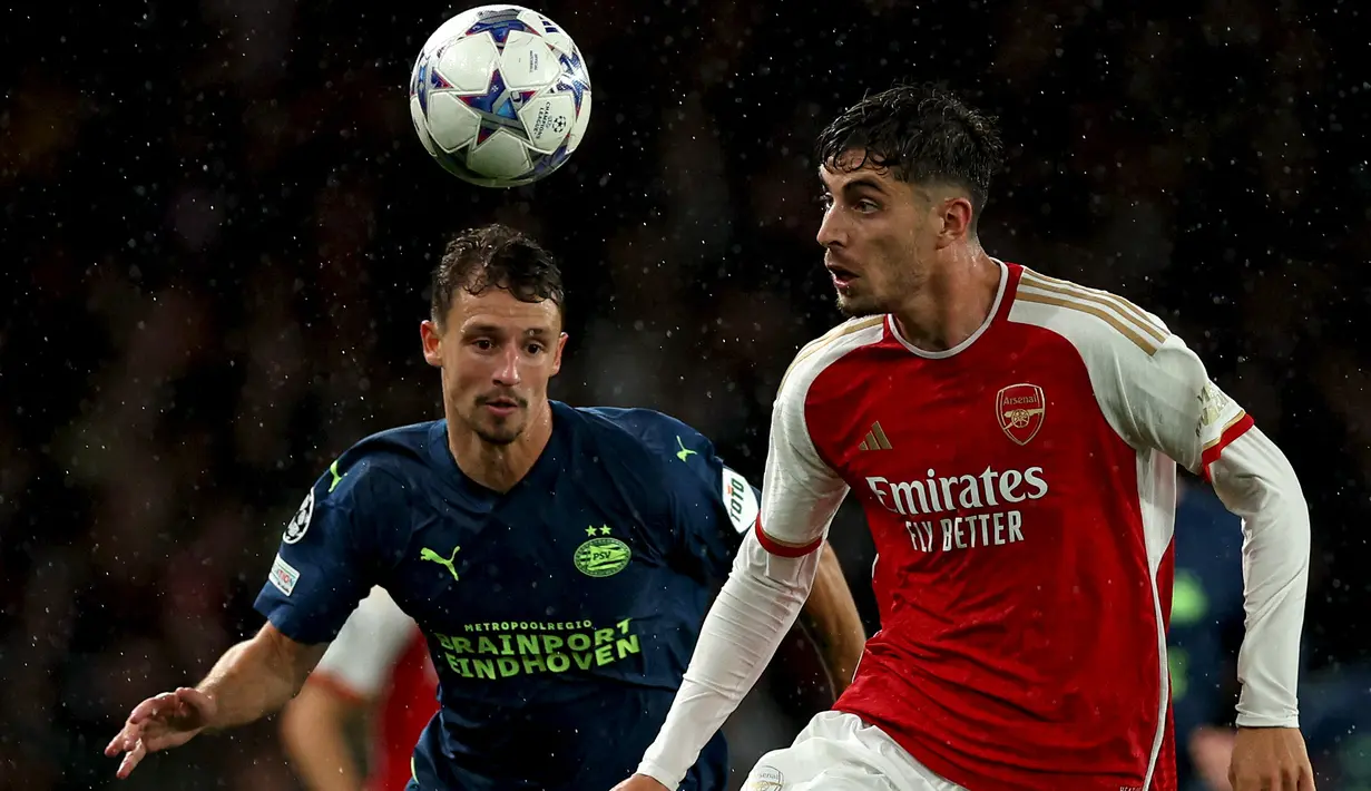 Bek PSV Eindhoven #18 Olivier Boscagli bersaing dengan gelandang Arsenal #29 Kai Havertz pada matchday pertama Grup B Liga Champions 2023/2024 di Stadion Emirates pada Kamis (21/9/2023) dini hari WIB. (AAdrian DENNIS / AFP)