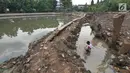 Seorang anak mencari ikan di situ Pedongkelan, Cimanggis, Depok, Rabu (28/11). Proyek normalisasi Situ Pedongkelan mengakibatkan keberadaan tumpukan lumpur bercampur sampah yang mengepung areal permukiman warga. (Liputan6.com/Herman Zakharia)