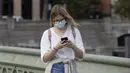 Seorang wanita yang mengenakan masker berjalan di Jembatan Westminster di London, Inggris (8/9/2020). Warga Inggris didesak untuk menangani pandemi dengan serius atau menghadapi "jalan bergelombang" di masa yang akan datang. (Xinhua/Han Yan)