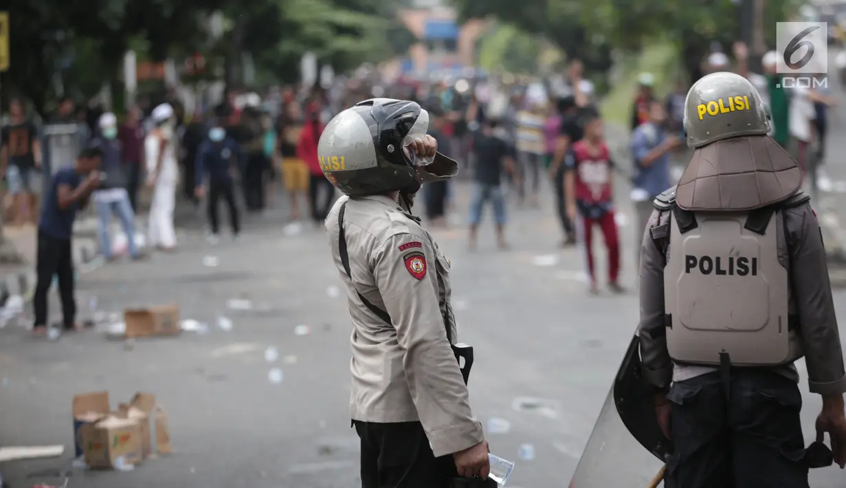 Polisi meminum air kemasan saat mengamankan aksi massa di kawasan Petamburan, Jakarta Barat, Rabu (22/5/2019). Hingga pukul 11.30 WIB, situasi berangsur kondusif. (Liputan6.com/Faizal Fanani)
