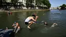 Setelah para pejabat meninggalkan tepi Sungai Seine, banyak perenang masih berada di air, beberapa bermain bola dan lainnya berlatih loncat dari kolam buatan. (JULIEN DE ROSA / AFP)