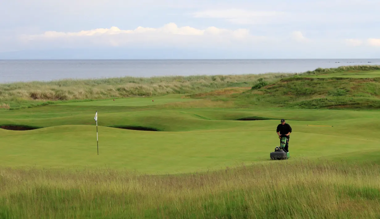 Pekerja memotong rumput lapangan golf di Golf Resort Trump Turnberry milik Donald Trump di Skotlandia, 13 Juni 2016. Dibeli Trump dari sebuah perusahaan yang bernama Dubai Leisurecorp, golf resort ini dibangun sejak 108 tahun lalu. (REUTERS/Tom Bergin)