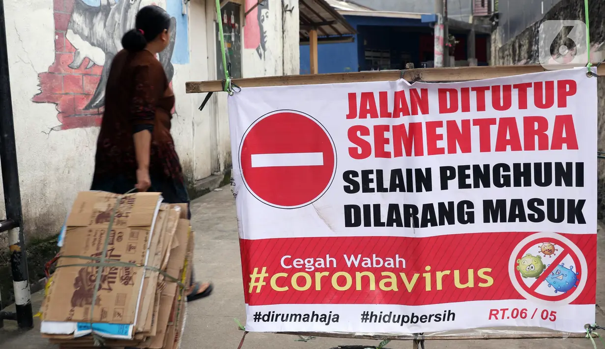 Warga memasuki salah satu gang yang ditutup secara swadaya di Kota Depok, Jawa Barat, Minggu (12/4/2020). Menteri Kesehatan menyetujui menerapkan Pembatasan Sosial Berskala Besar (PSBB) di wilayah Kota Depok yang akan dimulai, Rabu (15/4) dalam pencegahan COVID-19. (Liputan6.com/Helmi Fithriansyah)