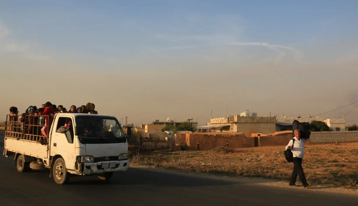 Warga melarikan diri menggunakan mobil dan berjalan kaki saat pasukan Turki memburu milisi Kurdi di Ras al Ayn, Suriah, Rabu (9/10/2019). Pusat Operasi Militer dan Koordinasi Pasukan Demokratik Suriah (SDF) melaporkan dua warga sipil tewas dalam serangan Turki tersebut. (AP Photo/Baderkhan Ahmad)