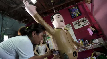 Seorang pekerja menempelkan pistol mainan ke boneka raja narkoba Joaquin "El Chapo" Guzman saat menyelesaikannya di Reynosa, Meksiko (21/7/2015). Guzman melarikan diri dari penjara melalui terowongan yang ia buat pada bulan lalu. (REUTERS/Daniel Becerril)
