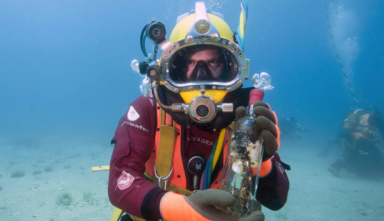 Penyelam menunjukkan botol anggur yang disimpan di dasar Laut Mediterania, Saint-Mandrier di Prancis, usai percobaan penyimpanan satu tahun, 15 Mei 2017. Percobaan untuk mengetahui dampak jika botol anggur itu disimpan lama di dalam air (Boris HORVAT/AFP)