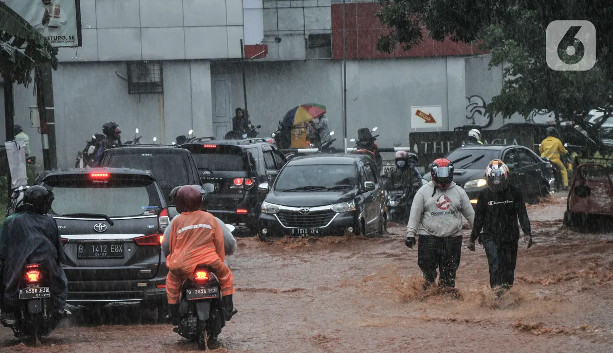 Warga berjalan kaki melintasi genangan lumpur di Jalan Raya Sawangan, Depok, Minggu (7/11/2021). Menurut warga setempat, banjir bercampur lumpur tersebut merupakan yang pertama kali yang diduga disebakan oleh proyek waduk perumahan yang belum rampung. (merdeka.com/Iqbal S Nugroho)
