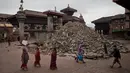 Beberapa orang melintas di sekitar kuil yang hancur akibat gempa berkekuatan 7,8  di sekitar Kathmandu, Nepal  (30/4/2015). Lebih dari 5.000 orang tewas akibat gempa yang meluluhlantakkan Nepal pada 25 April 2015 lalu. (Nicolas Asfouri/AFP)