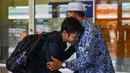 Seorang mahasiswa (kiri) yang dipulangkan dari karantina virus corona atau COVID-19 di Natuna menyalami keluarganya saat tiba di Bandara Internasional Sultan Iskandar Muda, Blang Bintang, Aceh, Senin (17/2/2020). Ada 13 mahasiswa Aceh yang mengikuti karantina di Natuna. (CHAIDEER MAHYUDDIN/AFP)