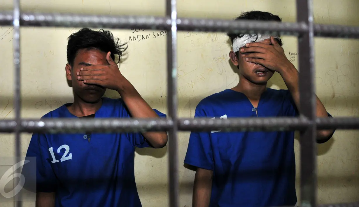 Dua pelaku penjambretan menutup wajahnya saat berada di dalam sel, Polsek Johar Baru, Jakarta, Senin (25/1/2016). Pelaku tertangkap dan dihakimi warga saat menjambret sebuah ponsel. (Liputan6.com/Yoppy Renato)