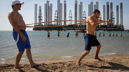 Anak-anak yang tergabung dalam sekolah kickboxing sedang berlatih di tepi Laut Kaspia dekat dengan bekas tempat pengeboran minyak era Soviet di kota Baku, Azerbaijan, Sabtu (27/6). (AP Photo/Dmitry Lovetsky)