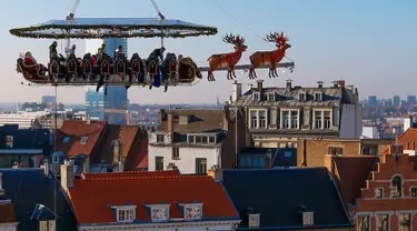 Para tamu menikmati makan malam di "Santa in the sky", yang diangkat dengan crane dan dihias menyerupai "Santa Sleigh" di Brussels, Belgia, 25 November 2016. Tempat ini didekorasi seperti kereta Santa Claus menjelang perayaan Natal. (REUTERS/Yves Herman)