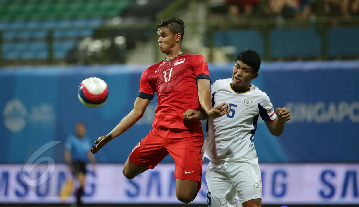 Pemain depan timnas Singapura U-23, Irfan Fandi Ahmad (kiri) melompat menahan bola saat berlaga melawan Filipina di laga grup A Sea Games 2015 di Stadion Jalan Besar, Singapura, Senin (1/6/2015). Singapura unggul 1-0. (Liputan 6.com/Helmi Fithriansyah)