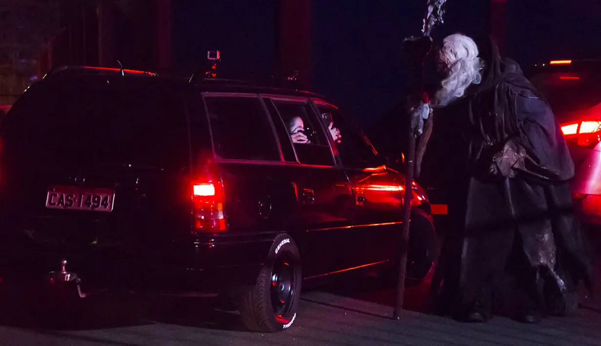 Pengunjung memotret seorang aktor dari dalam mobil mereka di taman hiburan horor Hopi Hari, pinggiran Vinhedo, Sao Paulo, Brasil, Jumat (4/9/2020). Karena pembatasan akibat COVID-19, taman hiburan horor Hopi Hari menampilkan pertunjukan secara drive-thru. (AP Photo/Carla Carniel)