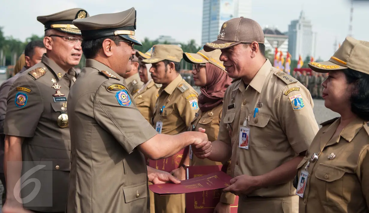 Djarot Saiful Hidayat menyalami pegawai negri sipil saat upacara hari jadi ke-67 Satpol PP dan ke-55 Satlinmas di Jakarta, Kamis (27/4). Upacara ini dihadiri ratusan Satpol PP dan Satlinmas di tingkat Provinsi DKI Jakarta. (Liputan6.com/Gempur M. Surya)