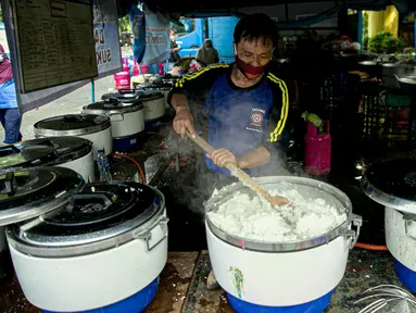 Petugas Taruna Siaga Bencana (Tagana) memasak nasi di Dapur Umum Kementerian Sosial di GOR Otista, Jakarta, Minggu (21/2/2021). Dalam sehari, petugas menyiapkan hingga 6.000 paket nasi kotak yang didistribusikan ke 11 kelurahan terdampak banjir. (Liputan6.com/Faizal Fanani)