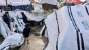 Pemerintah Gaza telah menyatakan kebutuhan mendesak akan sekitar 200.000 unit rumah prefabrikasi (rakitan) untuk menampung para pengungsi yang kehilangan tempat tinggal. Tampak dalam foto, seorang pria dan pemuda Palestina yang mengungsi menyesuaikan terpal tenda keluarga mereka saat wilayah tersebut dilanda hujan dan kondisi musim dingin yang dingin, di Kota Gaza pada 28 Desember 2025. (Omar AL-QATTAA/AFP)