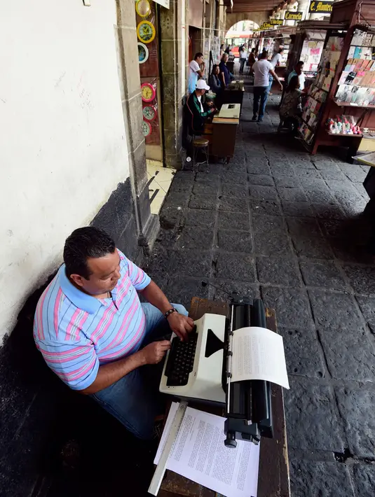 Seorang notaris serius menulis dokumen di Santo Domingo Square, Meksiko, (23/8). Notaris yang berada di pinggir jalan ini menerima jasa menulis surat terkait hukum perdata, lamaran kerja, wasiat, bahkan surat cinta. (AFP PHOTO/ALFREDO ESTRELLA)