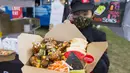 Penjual yang mengenakan masker memperlihatkan hidangan ayam goreng saat Festival Ayam Goreng di Toronto, Kanada, 20 September 2020. Festival yang digelar di tengah pandemi COVID-19 tersebut berlangsung pada 19-20 September 2020 dengan menghadirkan sekitar 30 jenis ayam goreng. (Xinhua/Zou Zheng)