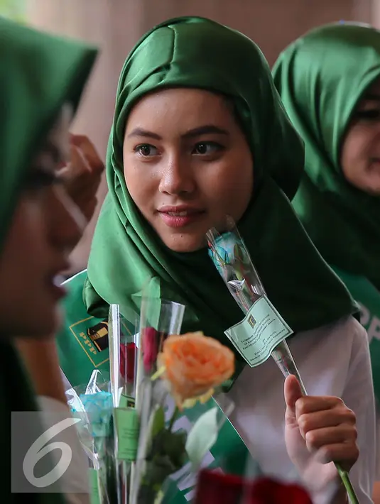 Simpatisan perempuan muda PPP memegang bunga untuk diberikan pada pegawai dan pengunjung di Kantor Kementerian Hukum dan Ham, Jakarta, Senin (11/1). Aksi damai tersebut mendesak penyelesaian konflik pengurusan partai PPP. (Liputan6.com/Faizal Fanani)