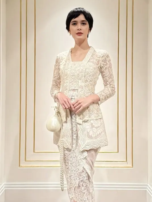 Renata tampil serba putih mengenakan kebaya brokat kutu baru dipadukan kain berbordir dari TOTON. Ia juga membawa tas mutiara putih yang ikonik. [@renata711]