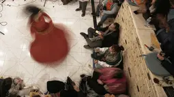 Terinspirasi dari Jalaluddin Rumi, tarian ini simbol alam semesta yang mengorbit Tuhan, di mana tangan kanan menengadah menerima hidayah, dan tangan kiri menghadap ke bawah membagikan cinta kasih. Tampak dalam foto, penari darwis wanita, Afnan Shaher, berputar saat disambut oleh para penggemarnya dalam pertunjukan keagamaan untuk menandai bulan suci Ramadan di Arab Digital Expression Foundation (ADEF), di Kairo, Mesir, Jumat 27 Februari 2026. (AP Photo/Amr Nabil)
