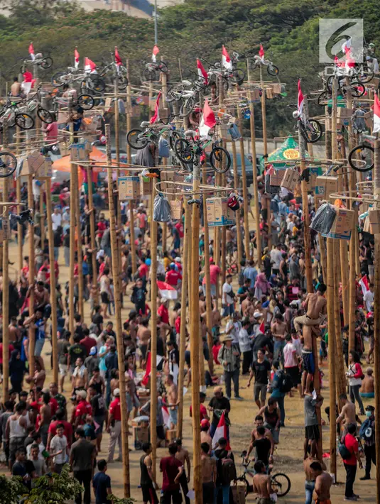 Warga mengikuti lomba Panjat Pinang Kolosal dalam rangka merayakan HUT ke-74 Kemerdekaan RI di Pantai Karnaval Ancol, Jakarta, Senin (17/8/2019). Sebanyak 174 batang pinang dengan beragam hadiah disediakan dalam lomba yang diikuti ratusan warga itu. (Liputan6.com/Faizal Fanani)