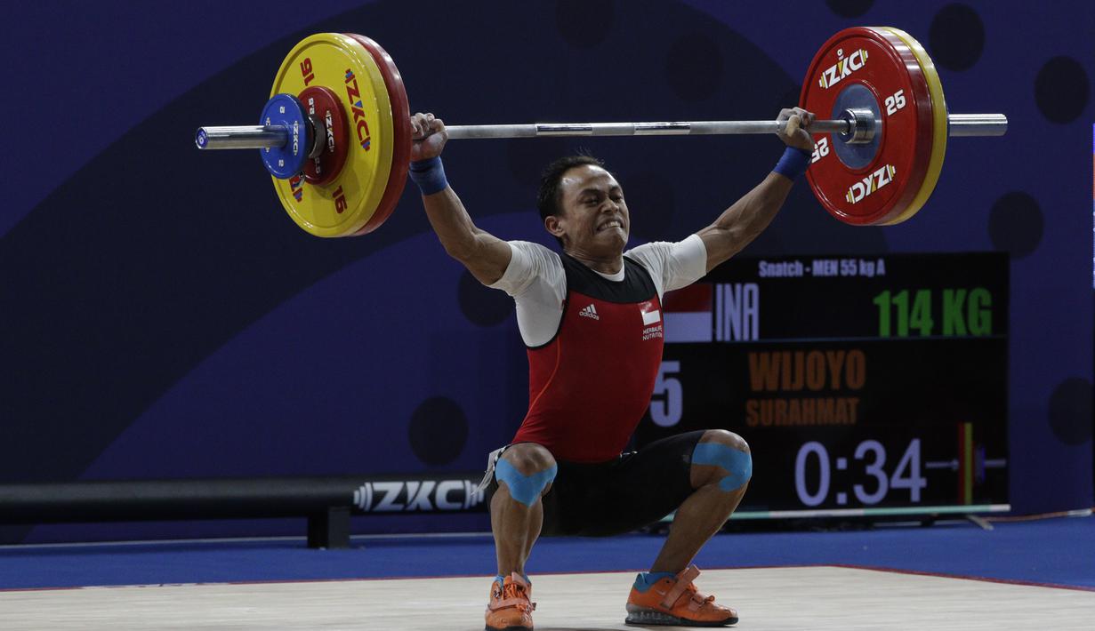 Lifter Suratman melakukan angkatan saat SEA Games 2019 cabang angkat besi nomor 55 kg di Stadion Rizal Memorial, Manila, Minggu (1/12). Dirinya meraih perak dengan total angkatan 250 kg. (Bola.com/M Iqbal Ichsan)