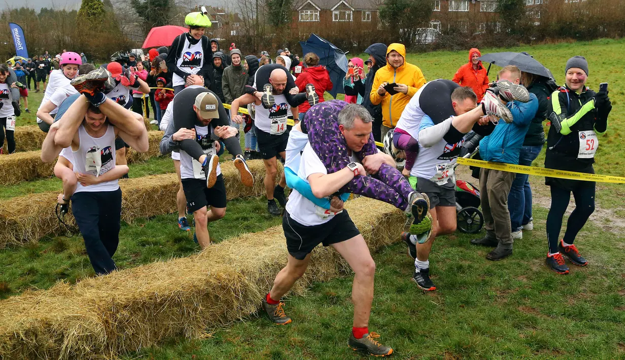 Para peserta melewati rintangan saat Lomba Lari Gendong Istri di The Nower, Dorking, Inggris, Minggu (3/3). Pemenang dari lomba ini akan berlaga di Finlandia untuk menjalani kejuaraan tingkat dunia. (Gareth Fuller/PA via AP)