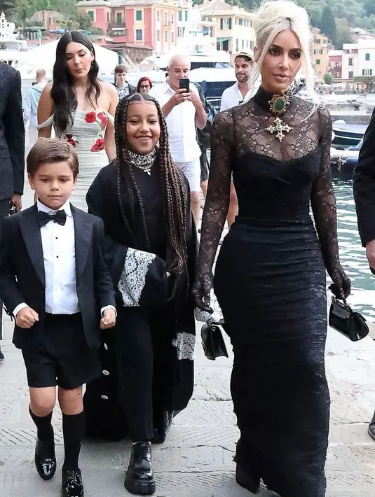 Kim Kardashian tampil nyentrik di hari pernikahan kakaknya itu. Perempuan 41 tahun itu tampil bergaya gothic mengenakan lace dress warna hitam. Gayanya disempurnakan dengan bros dan kalung choker, serta tata rambut high bun. (Instagram/enews).