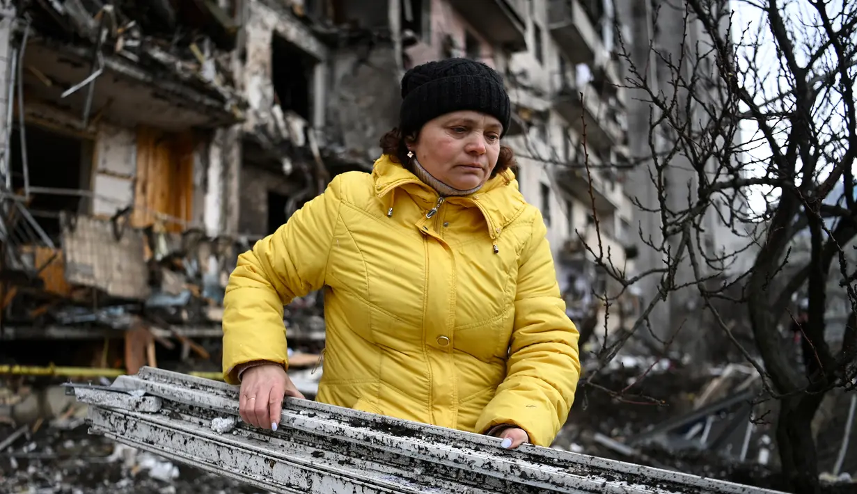 Seorang wanita membersihkan puing-puing di bangunan tempat tinggal yang rusak setelah peluru militer Rusia menghantam di Koshytsa Street, Kiev, Ukraina (25/2/2022). Serangan udara pada Kamis (23/2) dengan cepat merenggut puluhan nyawa dan membuat sedikitnya 100.000 orang mengungsi. (AFP/Daniel Leal)