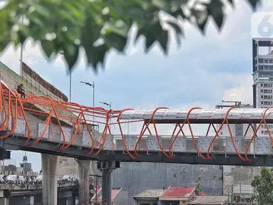 Pekerja menyelesaikan pembangunan jembatan penyeberangan orang (JPO) atau "Skywalk" di kawasan Kebayoran Lama, Jakarta, Sabtu (19/11/2022). Pemprov DKI Jakarta melalui Dinas Bina Marga DKI Jakarta membangun skywalk sepanjang 500 meter dengan desain dan cahaya artistik serta dilengkapi fasilitas lift juga eskalator. (Liputan6.com/Angga Yuniar)