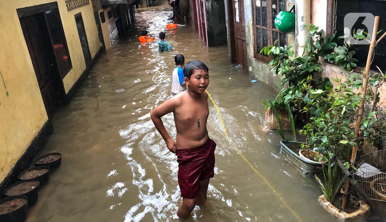 Anak-anak bermain di tengah banjir yang merendam kawasan Kebon Pala, Jakarta Timur, Selasa (25/2/2020). Akibat banjir yang tak kunjung surut, aktivitas warga di kawasan tersebut menjadi terganggu, terlebih dengan adanya pemadaman listrik. (Liputan6.com/Immanuel Antonius)