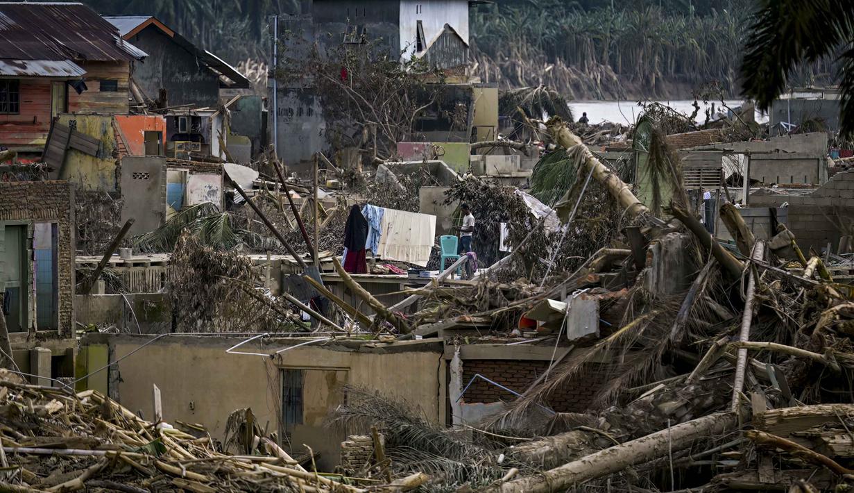 Infeksi kulit, diare, hingga infeksi saluran pernafasan biasanya muncul pada 10 hari pertama pasca terjadinya banjir. Tampak dalam foto, seorang perempuan menjemur pakaian yang baru saja dicucinya di tengah kondisi memprihatinkan akibat banjir bandang yang melanda daerah tersebut di Aceh Tamiang, Provinsi Aceh, pada Sabtu 6 Desember 2025. (YT HARIONO/AFP)