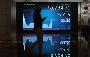 Pekerja melintasi layar pergerakan Indeks Harga Saham Gabungan (IHSG) di BEI, Jakarta, Rabu (16/5). Meski terjebak di zona merah, IHSG berhasil mengakhiri perdagangan di level 5.841. (Liputan6.com/Angga Yuniar)