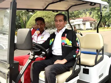 Presiden Joko Widodo atau Jokowi (kanan) bersama sprinter Lalu Muhammad Zohri (kiri) menaiki mobil golf di Istana Bogor, Jawa Barat, Rabu (18/7). Jokowi menjadi sopir Zohri ketika mengelilingi Istana Bogor. (Liputan6.com/Pool/Biro Pers Setpres)