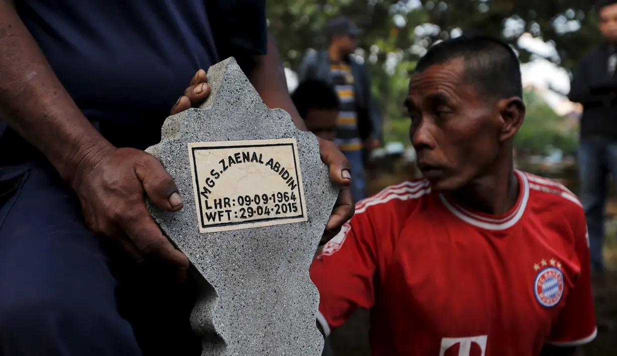 Seorang pekerja memegang batu nisan saat prosesi pemakaman terpidana mati Zainal Abidin di TPU di Cilacap, Jawa Tengah, Rabu (29/4/2015). Zainal satu-satunya terpidana mati asal Indonesia yang dieksekusi pada dini hari ini. (REUTERS/Beawiharta)