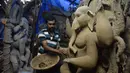 Seorang seniman India menyelesaikan pembuatan patung Dewa Hindu, Lord Ganesh di sebuah lokakarya di Hyderabad (19/8/2019). Patung ini dibuat dengan bahan-bahan ekologis untuk mengurangi polusi selama perendaman untuk festival Ganesh Chaturthi. (AFP Photo/Noah Seelam)