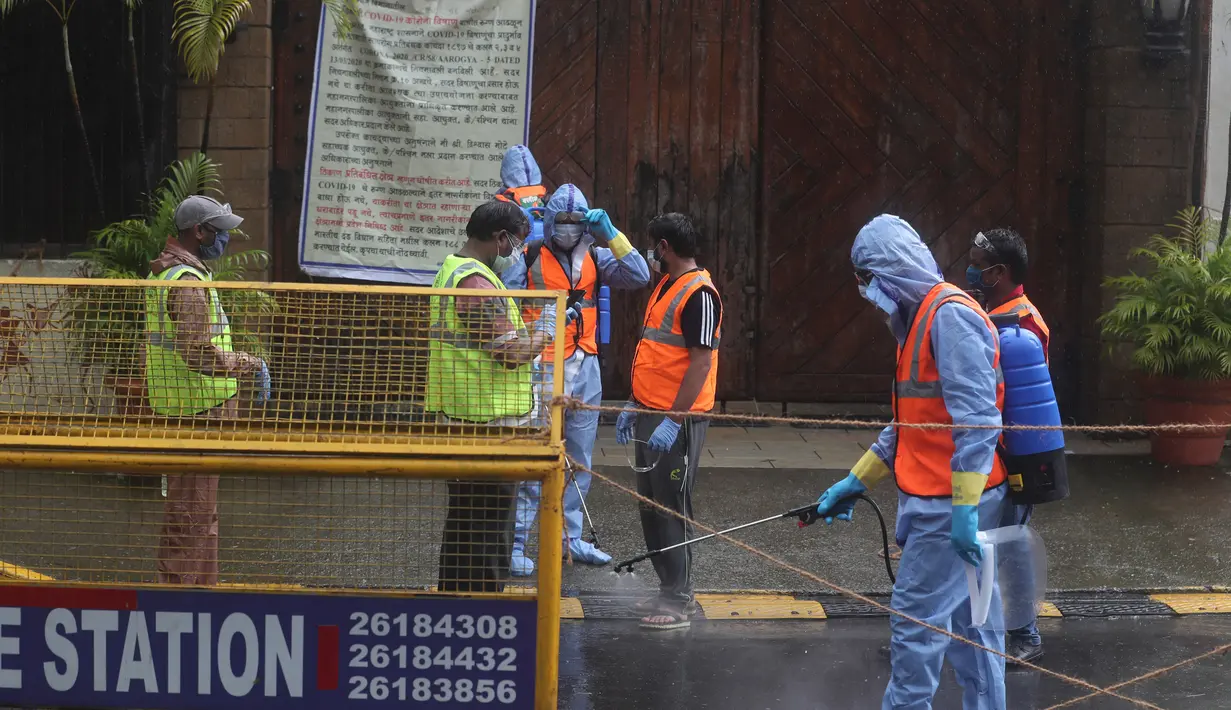 Pekerja otoritas sipil menyemprot disinfektan di pintu utama kediaman bintang Bollywood Amitabh Bachchan saat ia dinyatakan positif COVID-19 di Mumbai (12/7/2020).  (AP Photo/Rafiq Maqbool)