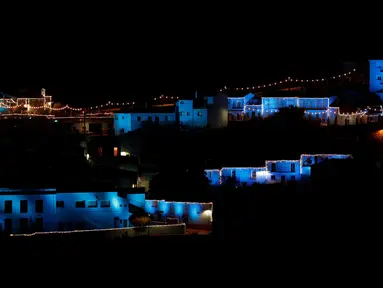 Lampu berwarna biru dinyalakan untuk menandai awal musim Natal di Juzcar, Selatan Spanyol, 2 Desember 2016. Semua bangunan di desa ini sengaja dicat berwarna biru untuk mempromosikan premier film baru "Smurfs: the lost village". (REUTERS/Jon Nazca)