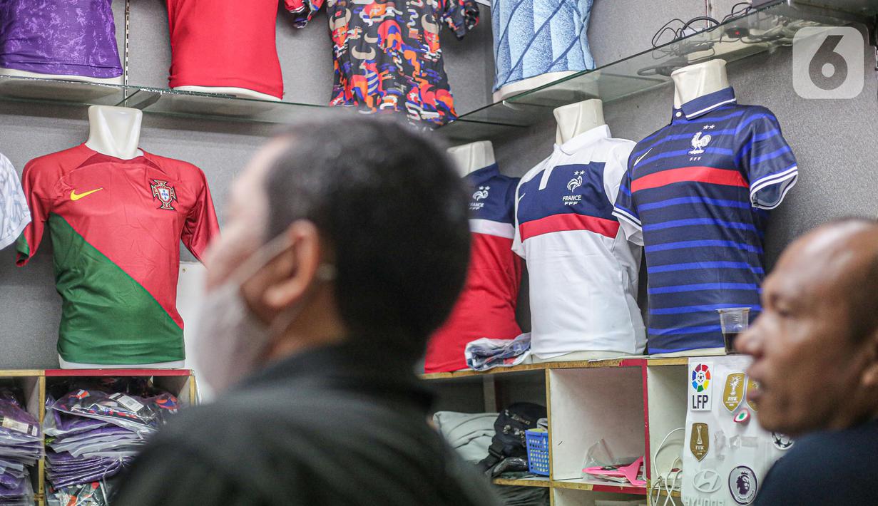 Pembeli melihat jersey tim peserta Piala Dunia 2022 Qatar di salah satu kios di Blok B Pasar Tanah Abang, Jakarta, Jumat (18/11/2022). Turnamen sepak bola Piala Dunia 2022 Qatar yang akan berlangsung selama sebulan dan dimulai pada Minggu (20/11/2022) turut mendongkrak penjualan jersey. (Liputan6.com/Faizal Fanani)